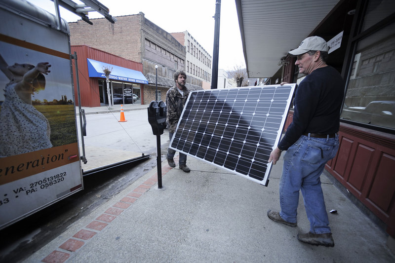 Evell Meade, left, and Mitch Mitchell carry a solar panel into a Williamson, W.Va., office on Wednesday as part of a jobs program focusing on alternative energy.