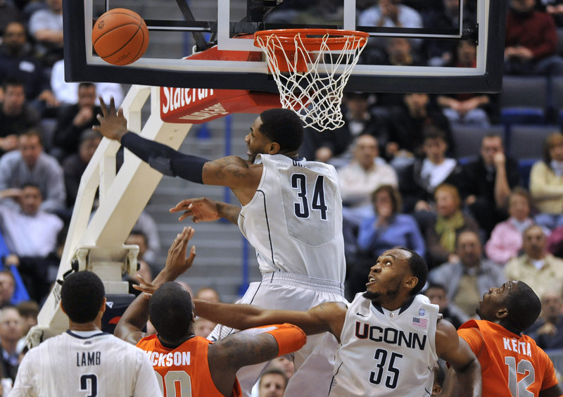 Alex Oriakhi of Connecticut swats away a shot by Syracuse's Rick Jackson, second from left, as Connecticut's Charles Okwandu, 35, defends during the first half of Syracuse's 66-58 win Wednesday night at Hartford, Conn.