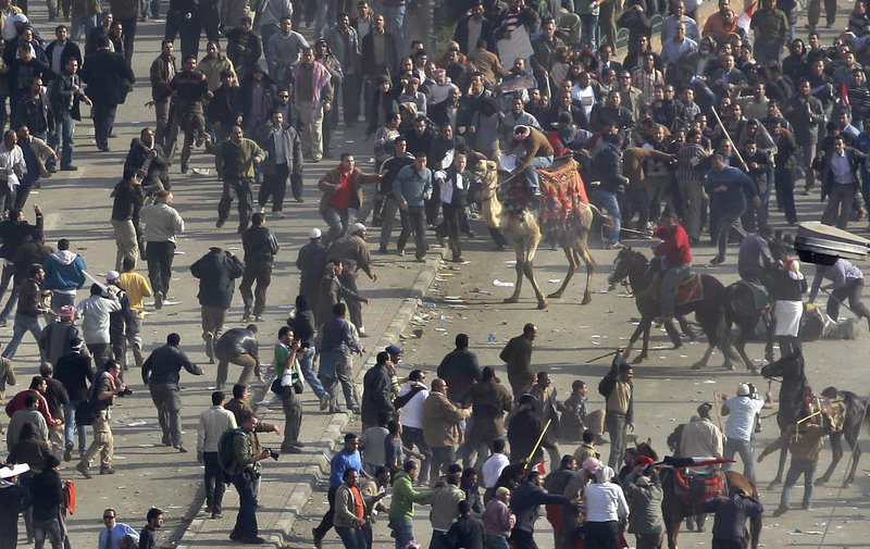 Pro-government demonstrators, below, some riding camels and horses and armed with sticks, clash with anti-government demonstrators, above, in Cairo’s Tahrir Square. Live television images showed people rushing from the scene with bloodied limbs and skulls.