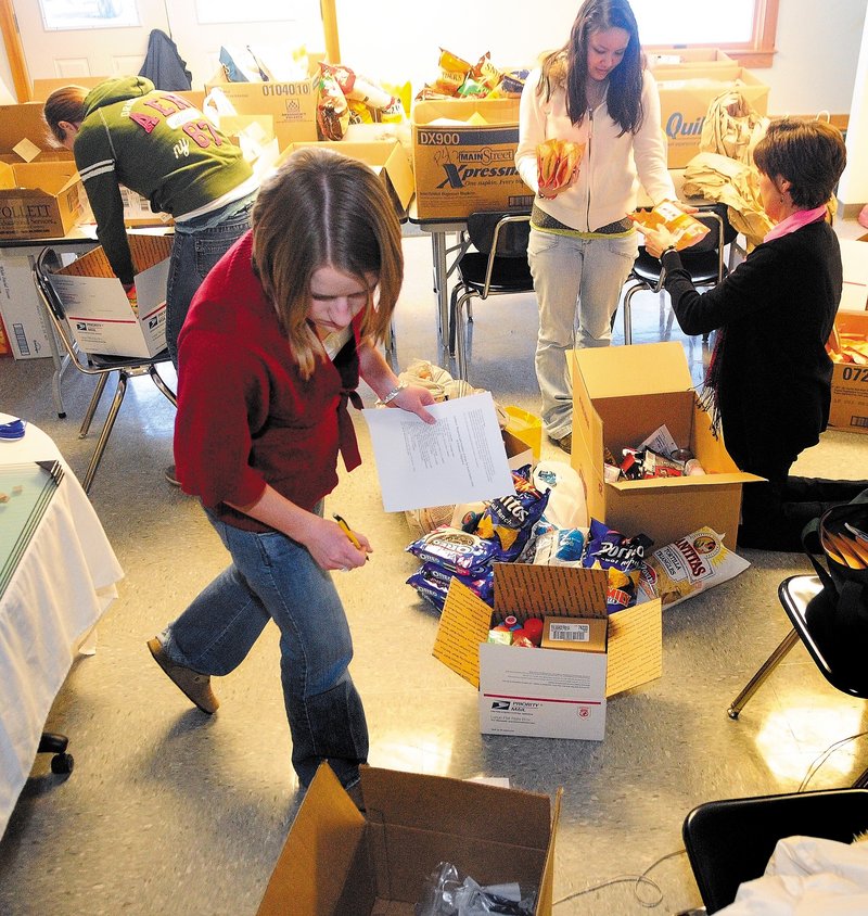 Erskine Academy students Alivia Spicer, foreground, Erica LeSieg, top left, and Brandi Moulton and staffer Diane Dow pack items for an Army brigade commanded by an Erskine graduate.