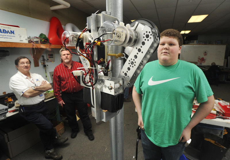Chris Fearing, a member of South Portland High School's robotics team, watches a "mini-bot" climb a 10-foot pole. Also watching the test, from left, are Steve Martin and Jim Henningsen, mentors to the group.