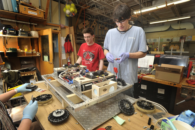 South Portland s robotics team captain Jacub Emery, right, and several teammates, including Gilead Biggie, work on attaching the wheels and chain drive onto a robot.