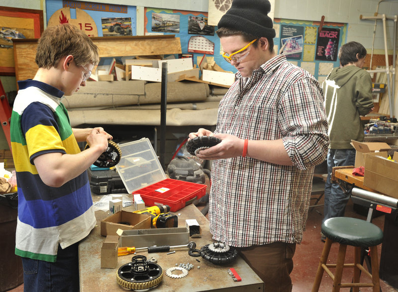 Team members Ross Usinger, left, and Garrett Libby assemble wheels for the robot.