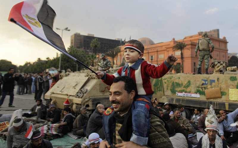 A boy sitting on the shoulders of an anti-government protester waves the Egyptian flag in front of armored personnel carriers Monday at the continuing demonstration in Tahrir Square in downtown Cairo.
