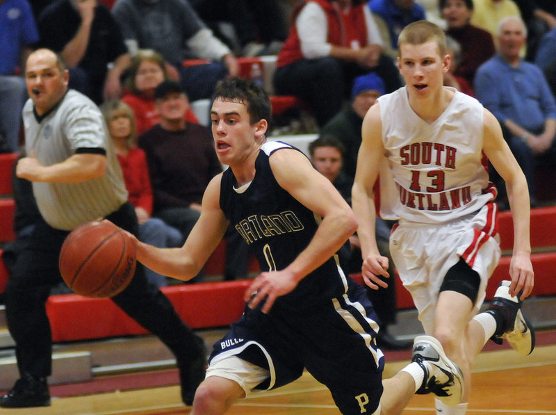Portland s Nick Volger drives to the basket as South Portland s Tanner Hyland follows him Tuesday night in South Portland. The Bulldogs held off the Red Riots to win their fourth straight.