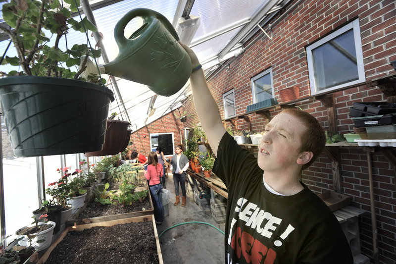 South Portland senior Brandon Gordon waters plants. The greenhouse is part of an effort to bring more experiential learning into the classroom.