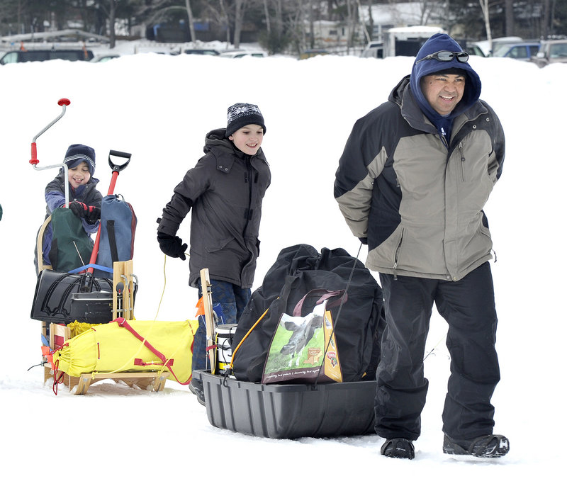 Rick San Pedro, right, of Topsham hauls ice fishing gear onto the lake with Alex Bryant, 10, center, and Will San Pedro, 9, to set up for the derby.