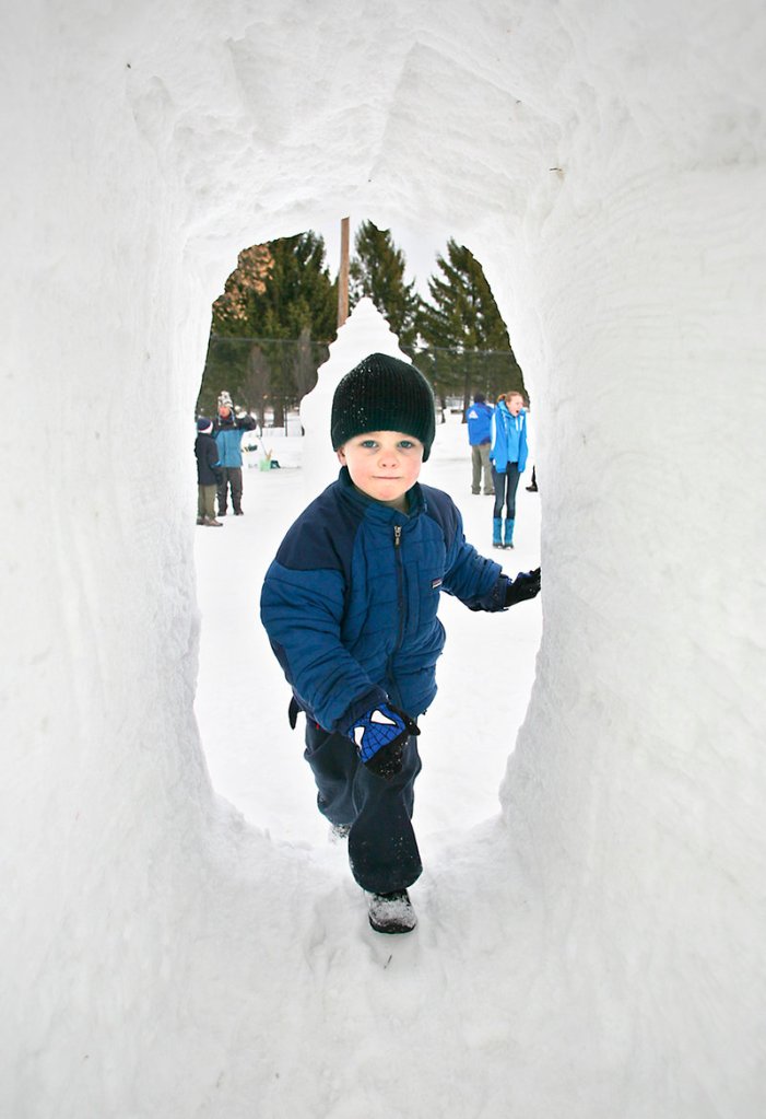 Thomas Healey, 4, of Falmouth climbs through a tunnel at the snow sculpture area during Saturday’s Portland WinteRush.