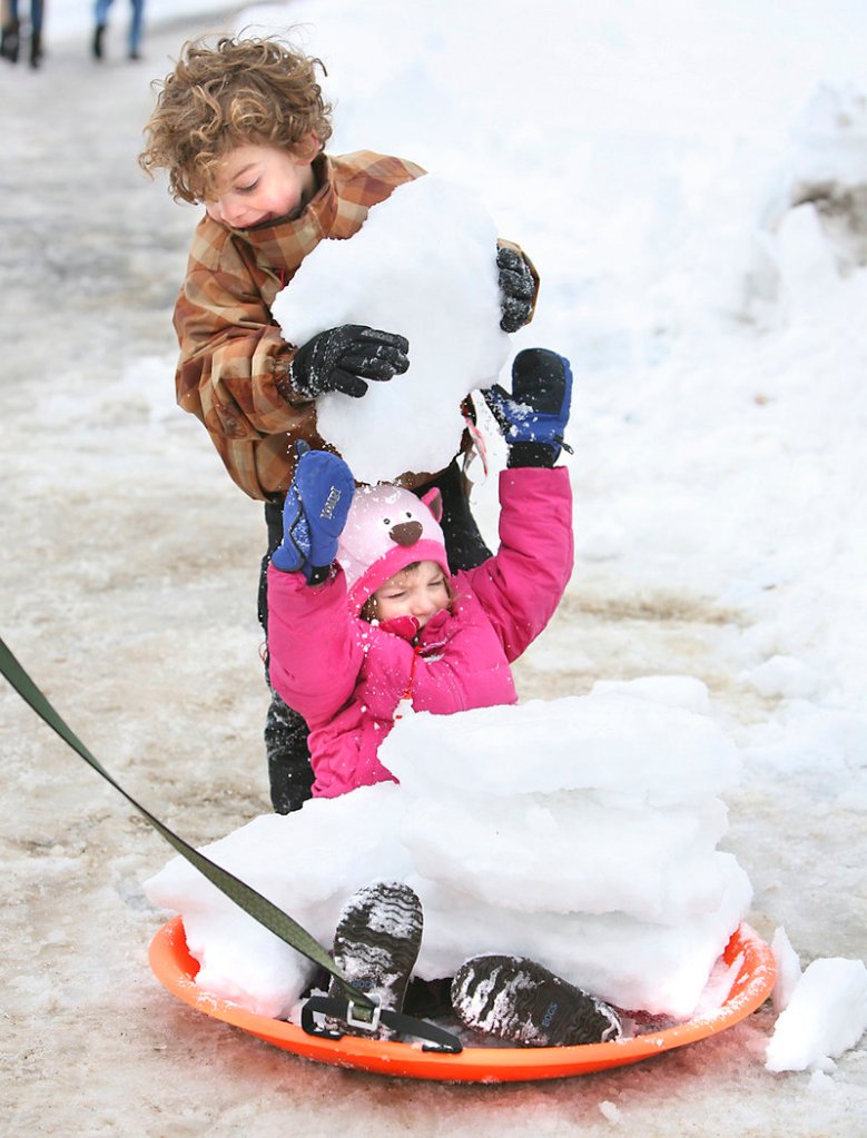 Torin Svedlow, 4, of Falmouth stacks chunks of snow on his 2-year-old sister Helen.
