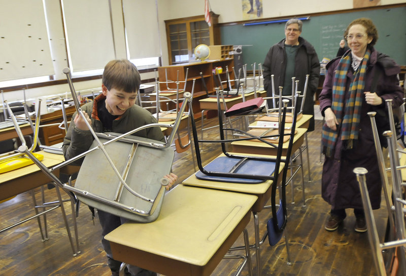 Daniel Baker, 10, a student at Nathan Clifford Elementary School in Portland, laughs as he puts his chair up at his desk Sunday during a farewell open house at the school. While showing off his classroom to his aunt and uncle, Linda Baker Bojarczuk and David Bojarczuk, he realized he left his chair down after school Friday and corrected his mistake.