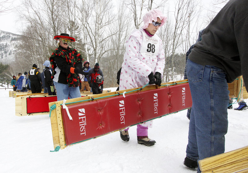 Patti Gwara of Bristol carries her sled up the hill on Saturday. Her two-person team is named Chute My Ash Is Dragon.