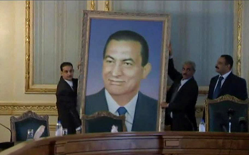 Officials remove a huge framed portrait of ousted Egyptian President Hosni Mubarak from the meeting room at the main Cabinet building in Cairo on Sunday. Egyptians are taking down images of Mubarak that have hung in public and private institutions throughout his three decades in power.