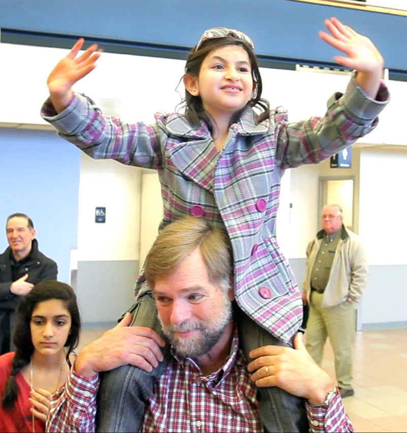 Sitting on Doug Rogers' shoulders, Noora Afif Abdulhameed waves to friends on Monday before boarding a plane home to Iraq.