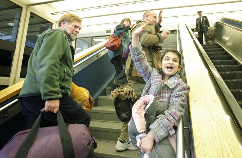 Noora Afif Abdulhameed waves to friends on Monday while walking upstairs at the Portland International Jetport to board a plane for the return trip to Iraq. At left are Doug Rogers and his wife, Susi Eggenberger, who helped to organize Noora's trips to Maine.