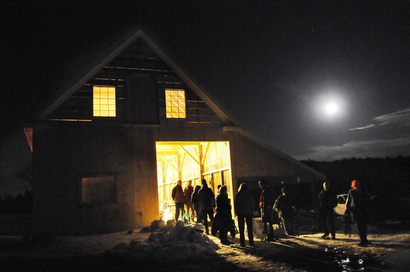 Hikers hang out around the well-lit barn under a bright moon at the DeWan farm after a moonlight snowshoe trek on Friday in New Gloucester.