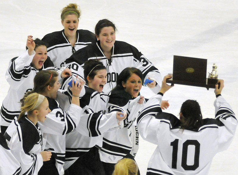 The St. Dom's girls' hockey team celebrates with the state championship trophy on Saturday night at the Colisee in Lewiston.