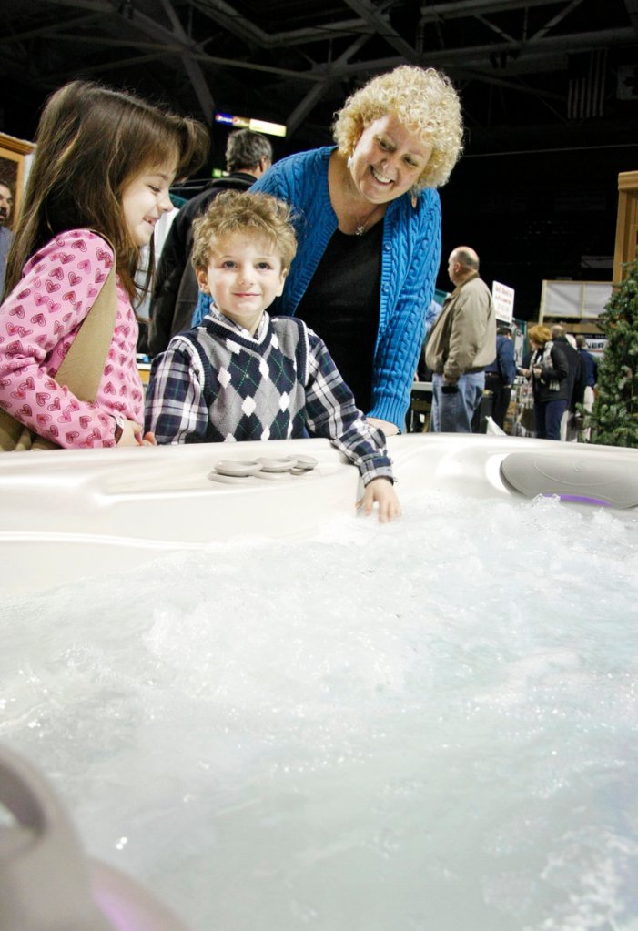 Seven-year-old Eric Ames of Sanford checks out the feel of the water as jets rev up in a Mainely Tubs hot tub on display at the home show Sunday. His sister Kristina Ames, 9, and their mom, Dee Ames, look on. The Ameses were scouting for ideas for a new home they plan to purchase this year.