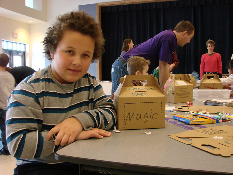 Wells third-grader Emanuel Diggs poses with the cardboard bank he decorated to hold spare change he collects during March as part of a schoolwide effort to fight homelessness. Emanuel's savings, as well as those of his classmates, will benefit agencies that assist homeless individuals.