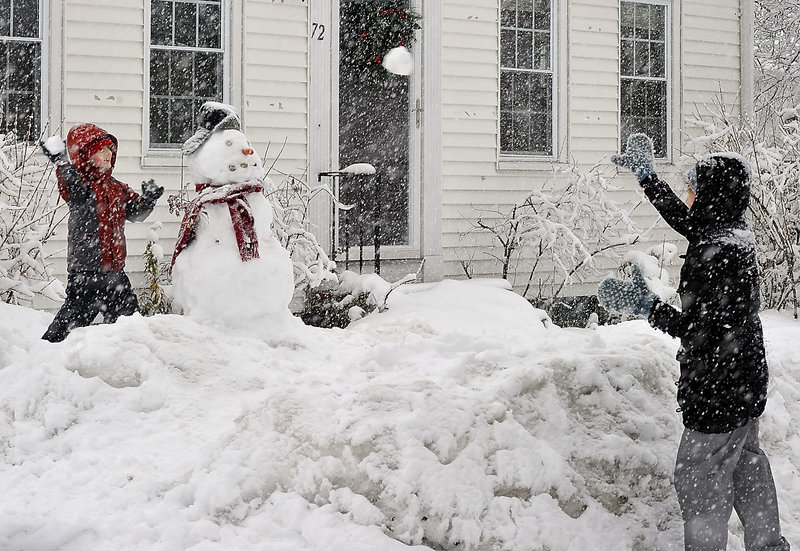 Aviva Shaw, right, and her son Brayden, 6, engage in a snowball fight refereed by a snowman they built Friday during the latest delivery of snow at their Vannah Street home in Portland.