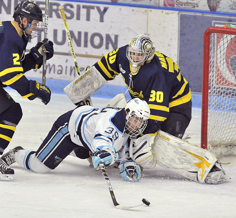 Joey Diamond of Maine lunges Friday night to try and sweep the puck past Merrimack goalie Sam Marotta after being knocked down by Fraser Allan in the third period of Maine’s 4-0 victory at Orono. The Black Bears have three games remaining before the Hockey East tournament.