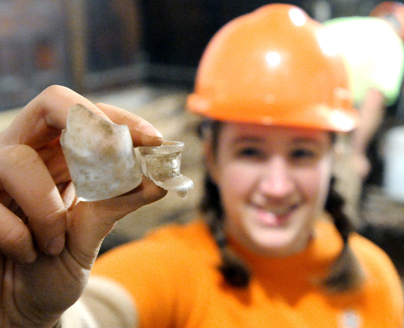 Field technician Robin Sherman holds pieces of a apothecary bottle found during the dig.