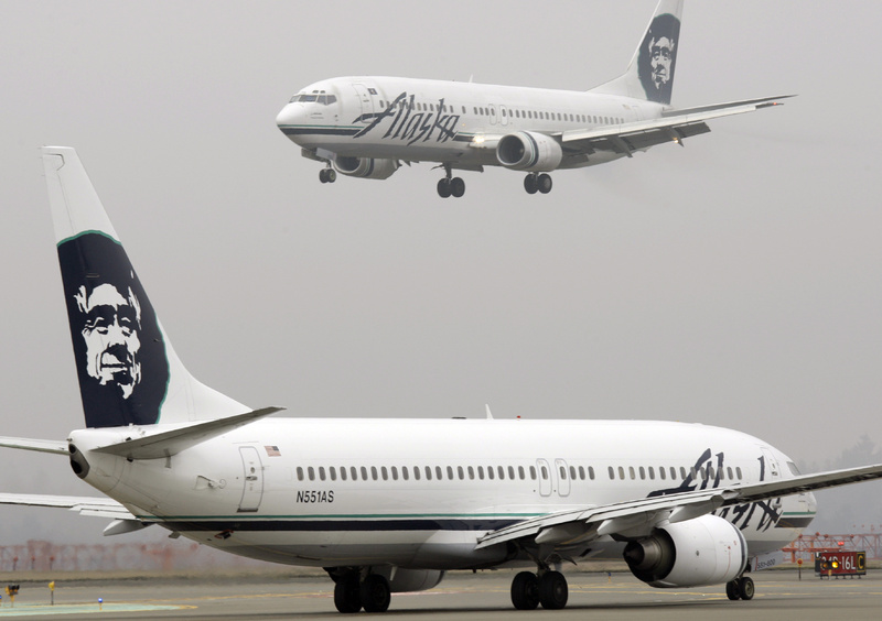 An Alaska Airlines plane comes in for a landing as another taxis for takeoff at Seattle-Tacoma International Airport in Seattle. Alaska Airlines and its Horizon Air affiliate had to cancel dozens of flights over the weekend because of a computer system failure.