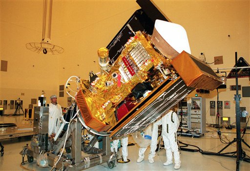 FILE - In this Jan. 11, 1999 file photo, workers at Kennedy Space Center in Florida watch as the Stardust spacecraft is lowered. NASA on Thursday, March 24, 2011 ordered its comet-hunting Stardust probe to burn its remaining fuel, setting off a series of events that will shut down the spacecraft after a 12-year career (AP Photo/NASA, File)