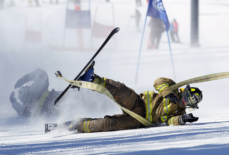 Dalton Bradley of the Rumford fire department crashes during a run in the 21st Annual Firefighter's Fundraising Race today at the Sunday River ski resort in Newry. Teams of five wearing firefighting gear carried a 50-foot hose while negotiating a giant slalom race course. The race benefits the Maine Handicapped Skiing program.