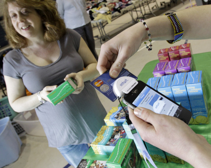 Alison Borodkin of Solon, Ohio, left, waits for Girl Scout Caroline Moore to run her credit card for the purchase of some Girl Scout cookies recently in Solon, Ohio.