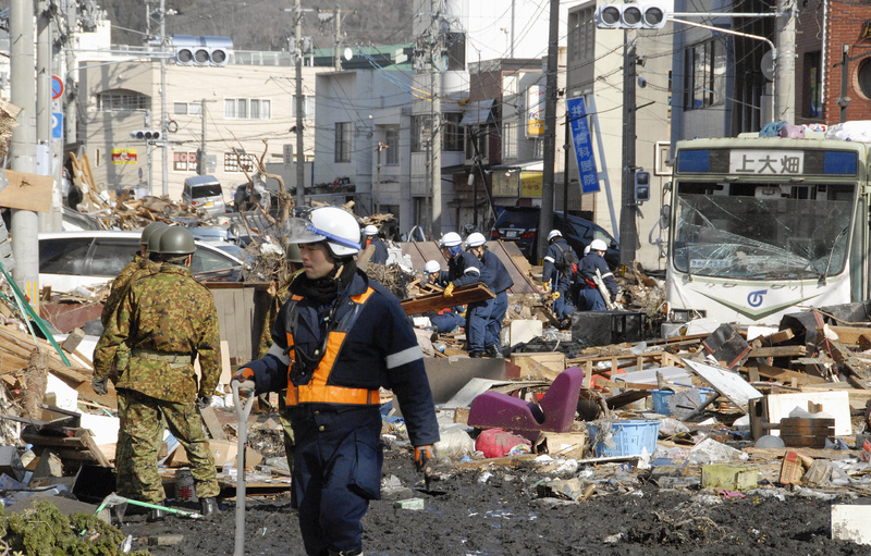Japanese soldiers and rescue workers try to remove rubble on a street in Kamaishi, northeastern Japan, today, one day after a giant quake and tsunami struck the country's northeastern coast.