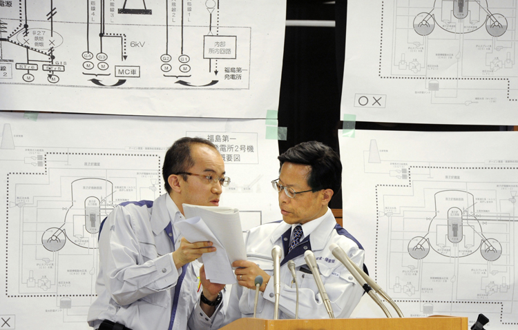 Nuclear and Industrial Safety Agency spokesman Hidehiko Nishiyama, right, huddles with his aide during a press conference on the crippled Fukushima Dai-ichi nuclear complex, in Tokyo today.