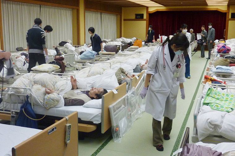 A care taker walks among elderly people fled to a hotel in Kamogawa, southeast of Tokyo, today. All the elderly people at a nursing home were moved from Fukushima, where the troubled nuclear complex is located, to a hotel owned by Japan Post Holdings.