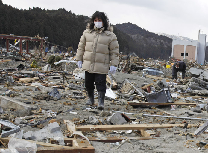 A woman searches for her missing husband through the earthquake and tsunami-hit town of Minamisanriku, Miyagi Prefecture today.