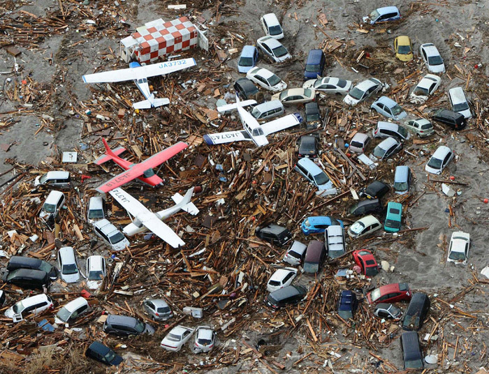 Planes and vehicles sit among the debris after they were swept up in the tsumani that struck Sendai airport in northern Japan today.