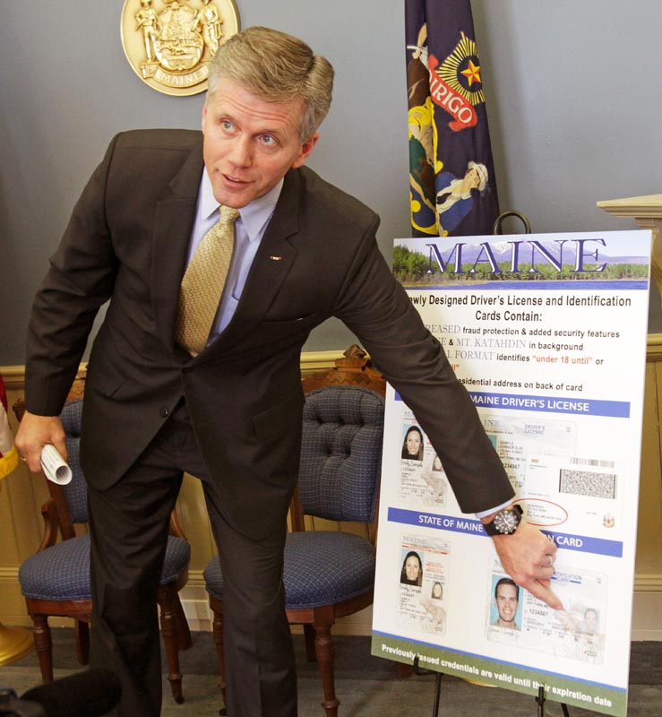 Secretary of State Charlie Summers points to a detail on a poster of the new Maine driver's license design featuring updated security enhancements, at a news conference in Augusta today.