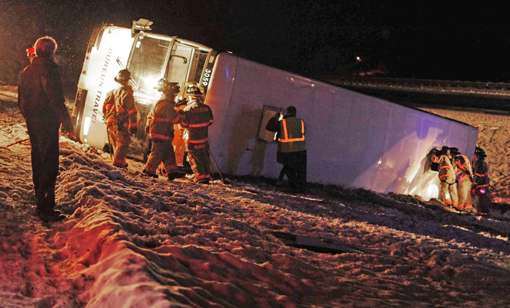 Rescue workers examine the tour bus that rolled over on Interstate 93 in Littleton, N.H. The bus was carrying about two dozen Koreans from Quebec to Boston when the driver lost control.