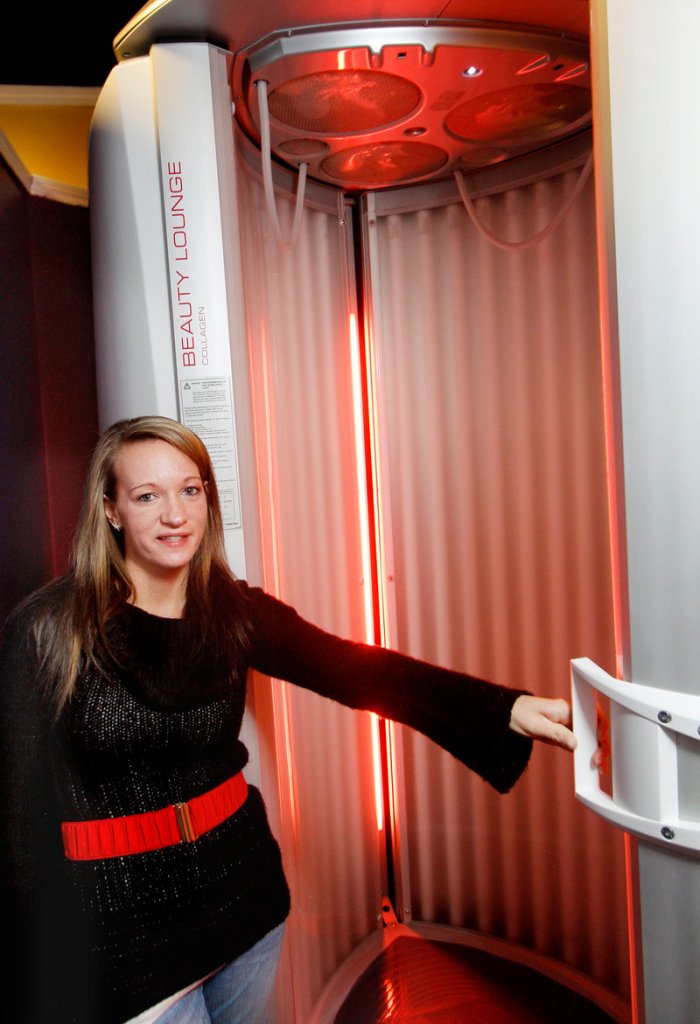 Cami Hondel, co-owner of Local Acapulco, stands with a red light therapy booth that provides an option for those who want to feel warmth and light without harmful UV rays – and without the tan.