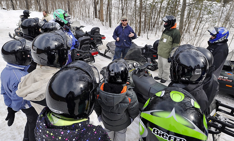 Guide Luke Gray, center, explains the travel and safety rules to a group about to go on a snowmobile excursion. Many of them are snowmobiling novices who came to Maine mostly to ski.