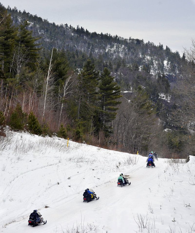 Vacationing snowmobilers cruise up a hill as they enjoy a ride organized by Sun Valley Sports in Bethel.