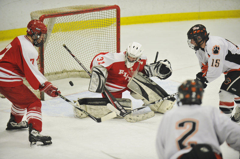 Tyler Audie of Biddeford sends the puck past South Portland goalie Dominic Desjardins during a 6-0 victory at the Biddeford Ice Arena. Josh Cobb of the Red Riots also moves in.