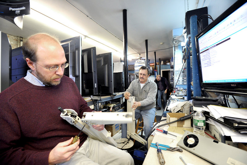 Reporter Ray Routhier, left, works with David Munster of David Munster's TV to repair a hospital TV's swing arm.