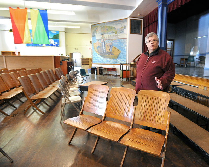 Portland schools facilities director Douglas Sherwood stands in the auditorium of the recently vacated Nathan Clifford Elementary School with old wooden seating. Behind him is a mural that will be relocated to the new Ocean Avenue school.