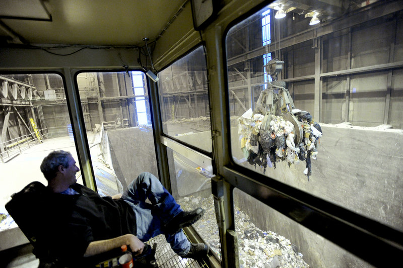 Crane operator Roland Coburn feeds trash into hoppers for the boiler at Ecomaine in Portland. A drop in wholesale electric rates has cut into revenue for the waste-to-energy plant. Somehow, we re going to make that up, says general manager Kevin Roche.