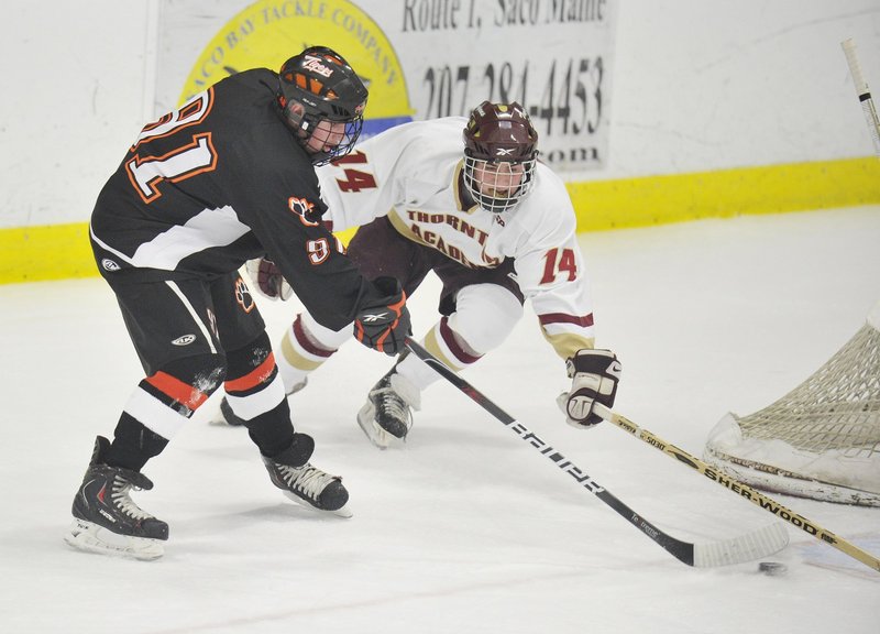 Biddeford’s Brady Fleurent, left, attacks the net as Thornton Academy’s Jonathan Dupee defends Jan. 5 at the Biddeford Ice Arena. The Tigers won that game 5-1 and a Feb. 5 rematch, 5-4. But the Trojans are riding a seven-game win streak into tonight’s Western Class A final.