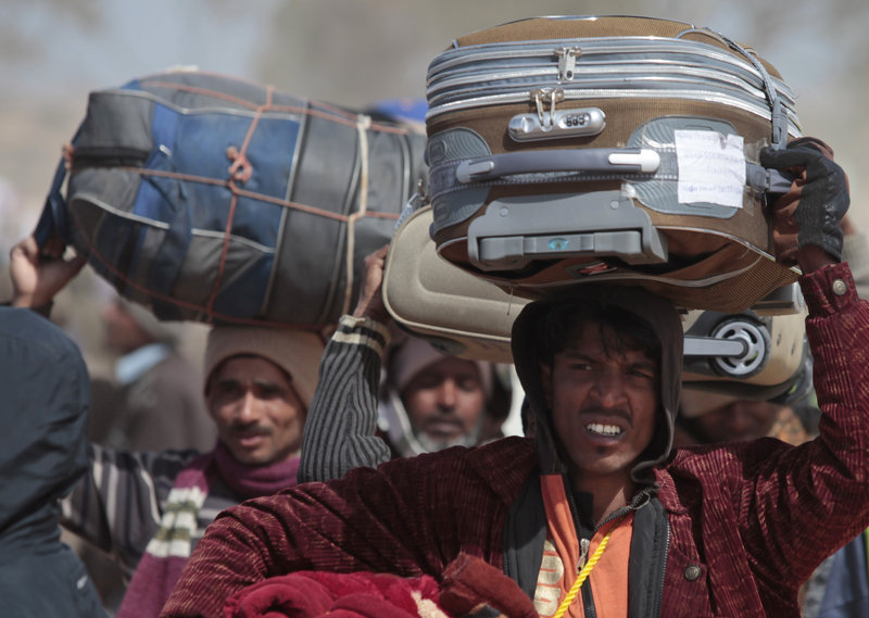 Men from Bangladesh, who used to work in Libya and fled the unrest in the country, carry their belongings as they arrive in a refugee camp at the Tunisia-Libyan border on Wednesday.