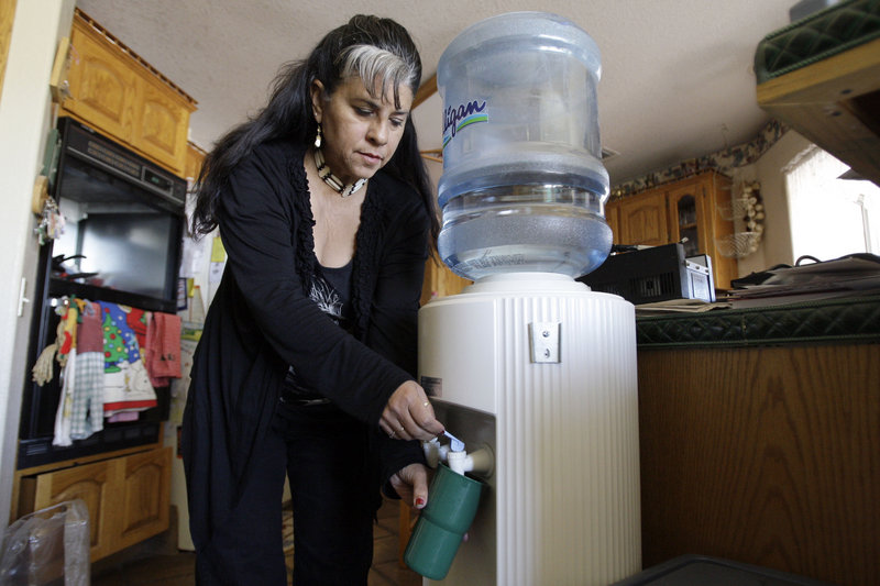 Roberta Walker draws bottled water at her home in Hinkley, Calif., a small community whose struggles with contaminated groundwater inspired the movie “Erin Brockovich.” The pollution has again seeped into the area’s groundwater.