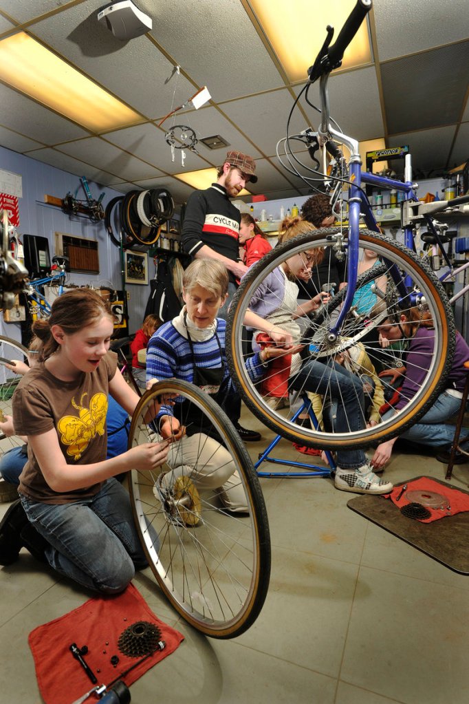 Jamie White, left, and volunteer Alicia Soliman work together on cleaning and replacing the rear hub of a bicycle during a Bike Monkeys class at the Community Bicycle Center.