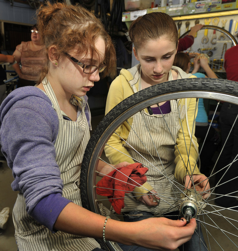 Mercedes McCorrison, left, and Priscilla Work, both of Westbrook, replace a rear hub assembly after cleaning and greasing it.
