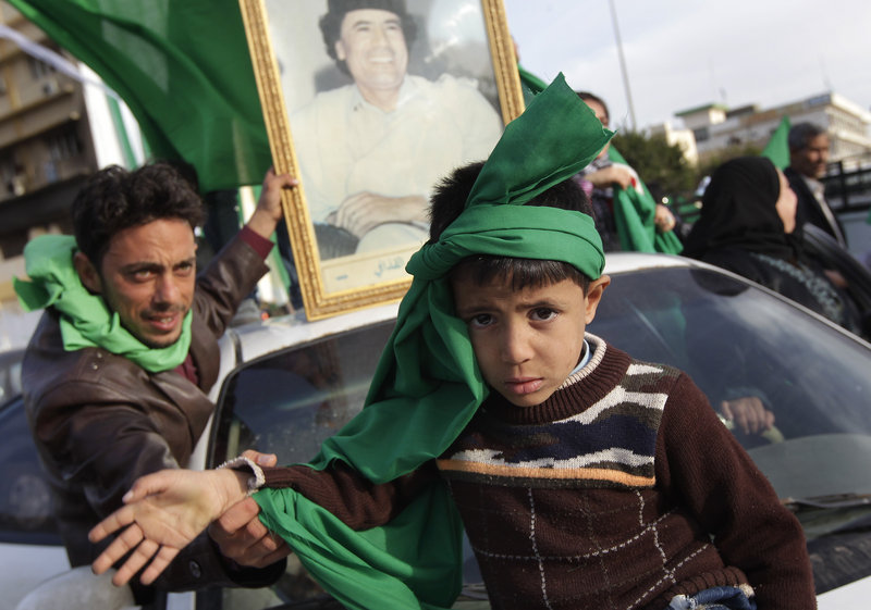 A supporter of Libyan leader Moammar Gadhafi coaxes a child to raise his arm for the photographer during a government-organized visit for foreign media Friday in Zawiya, 30 miles west of Tripoli. Gadhafi’s regime has gained momentum with the capture of Zawiya.