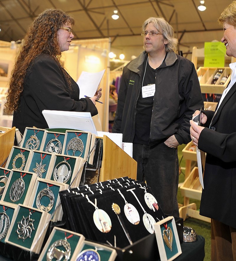 Julie Leighton, left, store manager at the Seashore Trolley Museum in Kennebunkport, and her husband, Glen, talk with Sharon Duffield, of Lovell Designs in Portland, about Lovell Designs’ products at the New England Products Trade Show.